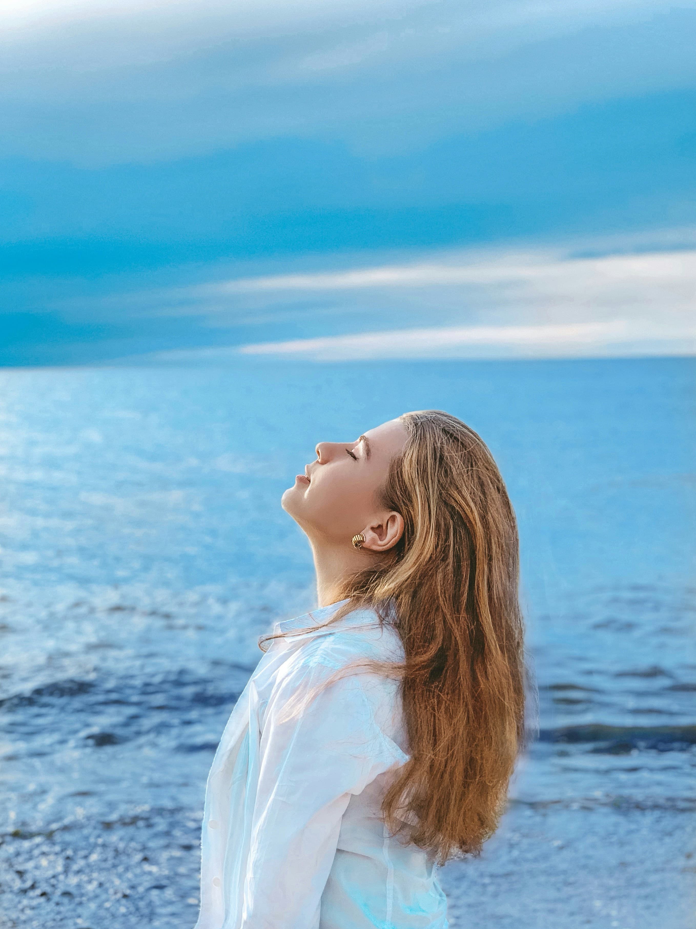 Woman holding her head high against a background of ocean and sky