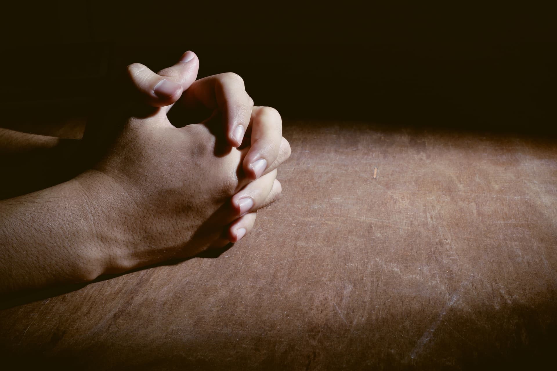 Hands clasped in prayer in warm light